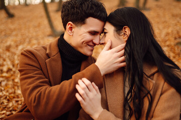 Young couple in love walking in the park on a autumn day. Enjoying time together. Stylish and loving couple enjoying each other in the autumn forest. 