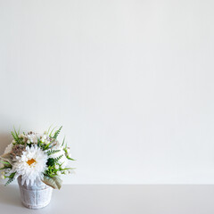 Wall mockup with pot of flowers on white surface. Copy space.