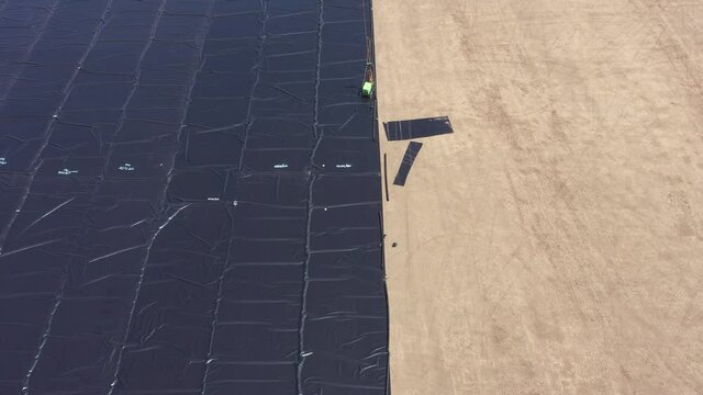 Water reservoir construction site with newly installed plastic lining sheets, Aerial view.
