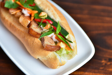 Delicious Vietnamese style hot dog bahn mi in a crusty baguette bun with pork, herbs, vegetables
