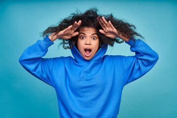 Young ethnic girl with a naughty curly hairstyle on a blue background.