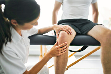physiotherapist doing treatment with patient in bright office check knee