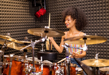 Fototapeta na wymiar Laughing vivacious young woman playing drums