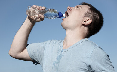 guy drinks water from a bottle during training in nature