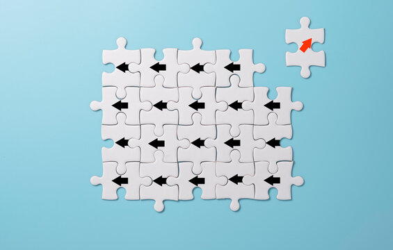 Red arrow print screen on white jigsaw puzzle  move out and chang direction from black arrows. It is business disruption and different thinking idea concept.