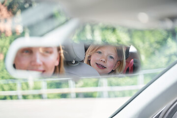 Happy woman travelling by car with cute daughter
