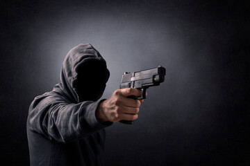 Hooded man with a gun in the dark