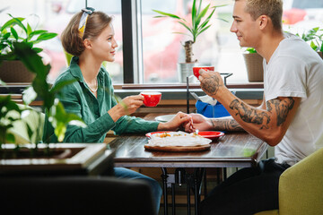 Man and woman on date in a cafe, they are drinking coffee, staring at each other