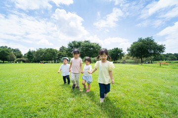 青空の下、手を繋いで元気に歩く子供たち