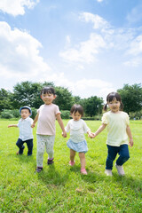 Fototapeta premium 青空の下、手を繋いで元気に歩く子供たち