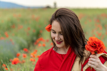 Naklejka premium Yound girl dressed in Indian Sari in a poppy flower garden