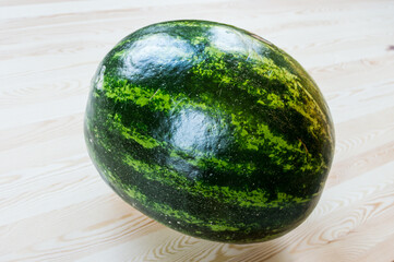 A large watermelon on a wooden table.