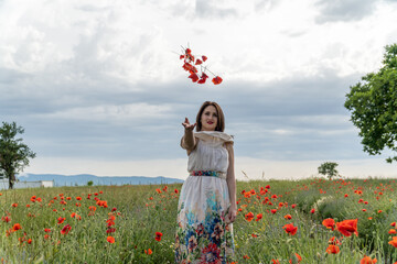 Young girl throwing poppy flowers in a field