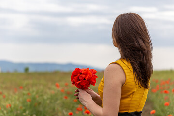 Naklejka premium Girl dressed with yellow dress in a poppy garden