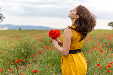 Girl dressed with yellow dress in a poppy garden