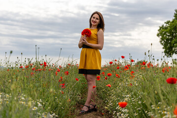 Girl dressed with yellow dress in a poppy garden