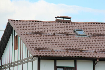 roof with new brown roofing tiles on residential property. banner on  roof for roofers. concept for...