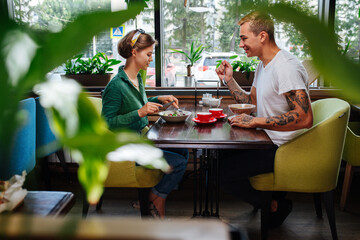 Man and woman on date in a cafe, eating their meals in front of each other