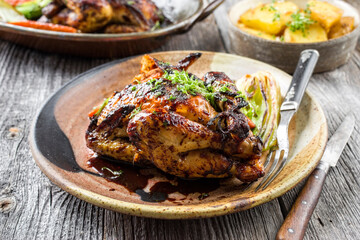 Traditional French spring chicken with fried potatoes and vegetable offered as close-up on a design plate