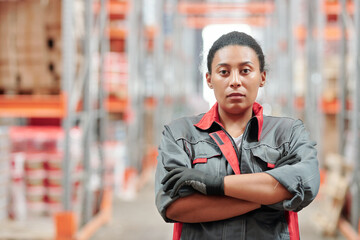 Young serious mixed-race female worker of warehouse crossing arms by chest
