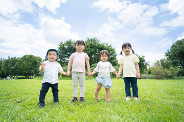青空の下、手を繋いで一列に並ぶ子供たち