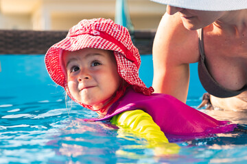 2-3 years old child with mother in swimming pool learn to swim. Summer at home concept.