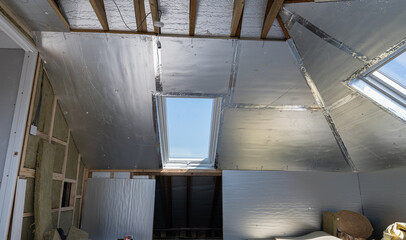 Loft conversion, unfinished project, silver insulation, roof windows wood structure, selective focus