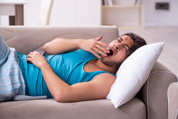 Young man waking up at home