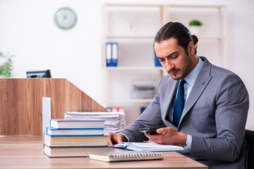 Fototapeta premium Young male businessman reading books at workplace