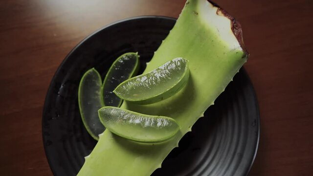 Aloe vera plant slices on a plate, wooden table. Natural cosmetics, body care