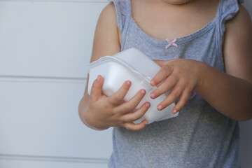 Child trying to open takeaway foam lunch box. Single use food container, close up.