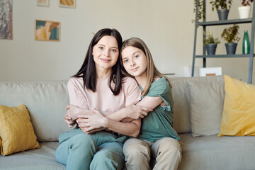 Fototapeta premium Cute blond teenage girl in casualwear embracing her mother in front of camera
