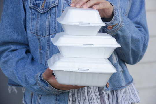 Woman's hands holding takeaway foam lunch boxes. Single use food containers, close up.