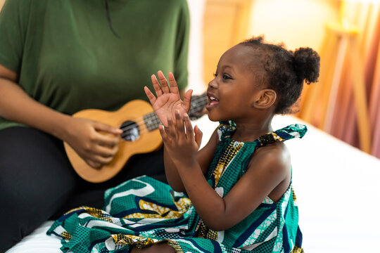 Happy Mom With Her Daughter Playing Guitar And Singing Together At Home, Happy Family