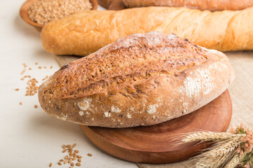 Different kinds of fresh baked bread on a white wooden background. side view, selective focus.