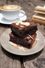 Chocolate brownies cake topped with sliced almonds placed on a gray brown plate.