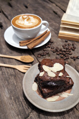 Chocolate brownies cake topped with sliced almonds placed on a gray brown plate.