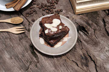Chocolate brownies cake topped with sliced almonds placed on a gray brown plate.