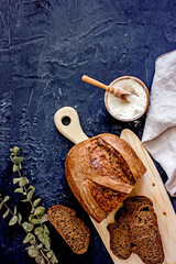 Country sourdough bread on a wooden light board on a dark background, top view, vertical background, copy space, flay lay, top-down food