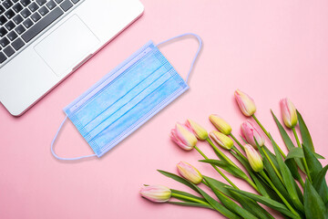 Protective mask on pink office desk background, business and coronavirus concept