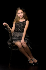 Obraz na płótnie Canvas Portrait of a little girl sitting on an old Viennese chair, black background.