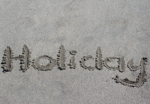 "Holiday" written in sand beach