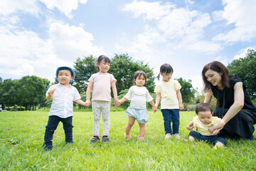 Obraz premium 青空の下、手を繋いで一列に並ぶ子供たち