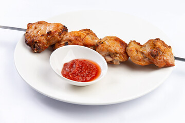 Shish kebab on a skewer in a plate on a white background
