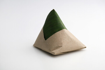 Nasi lemak wrapped with banana leaf isolated on white background. Nasi lemak is a Malay cuisine dish consisting of fragrant rice cooked in coconut milk and pandan leaf.