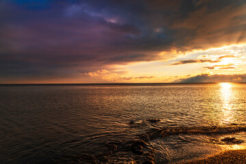 Beautiful landscape. Bright golden sunset with dramatics clouds over the lake. 