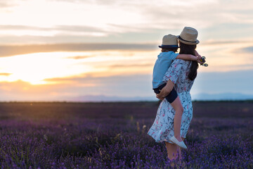 Madre e hijo contemplando puesta de sol en campo de lavanda