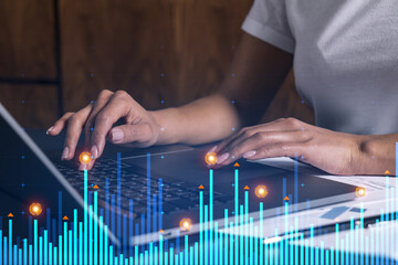 Businesswoman typing on computer in office. Fiancial graph hologram. Double exposure.