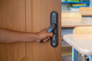 child's hand opens the door in the classroom