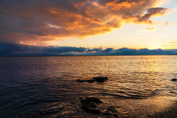 Beautiful landscape. Bright golden sunset with dramatics clouds over the lake. 